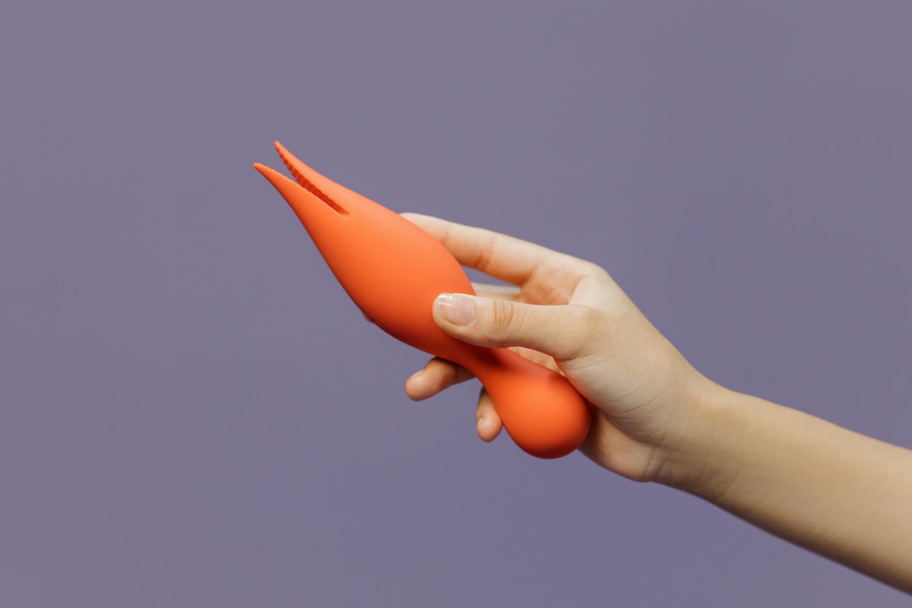 A hand holding a lemon vibrator against a minimalist purple backdrop, symbolizing modern intimacy between partners