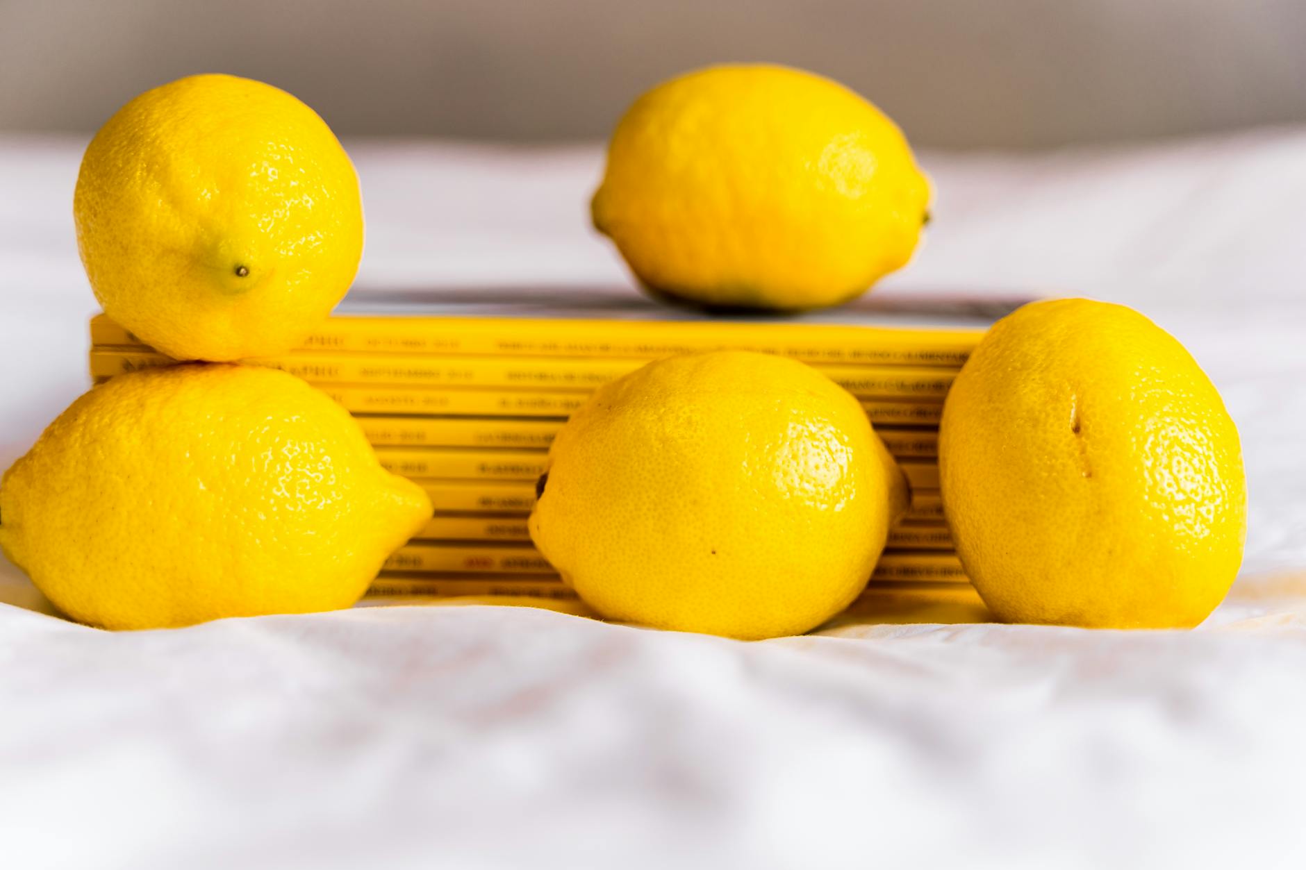 Fresh lemons arranged with stacked books on a white tablecloth, symbolizing natural wellness and clarity